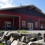 A tile red post-frame riding arena with overhead doors, timber accents, and soffits