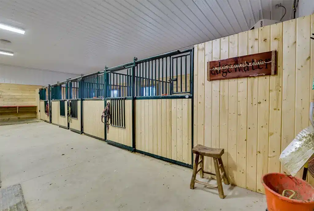 A sable post-frame riding arena with overhead doors, an open lean-to and kickwall