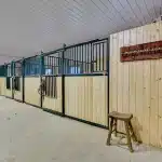 A sable post-frame riding arena with overhead doors, an open lean-to and kickwall
