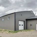 A sable post-frame riding arena with overhead doors, an open lean-to and kickwall