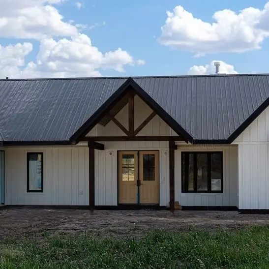 A white white post-frame Homestead with loft, with an overhead door, soffits, and timber accents