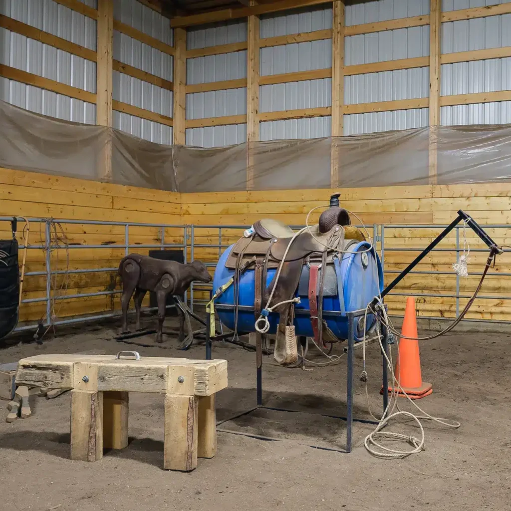A dark red post-frame riding arena with a chain overhead door