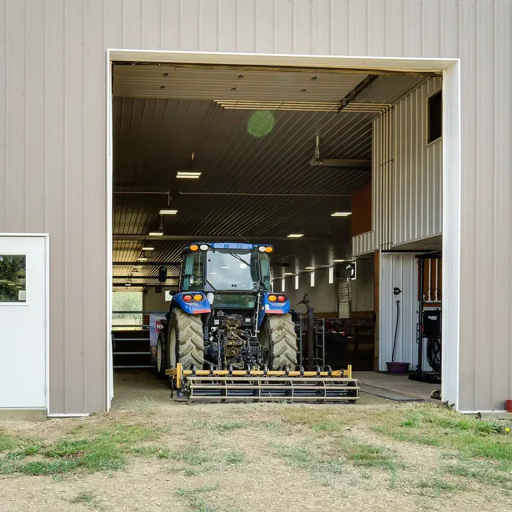 A buckskin post-frame riding arena with two overhead doors
