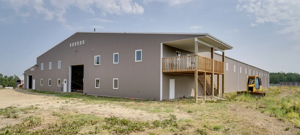 A buckskin post-frame riding arena with two overhead doors