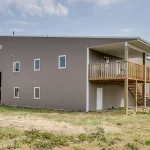 A buckskin post-frame riding arena with two overhead doors