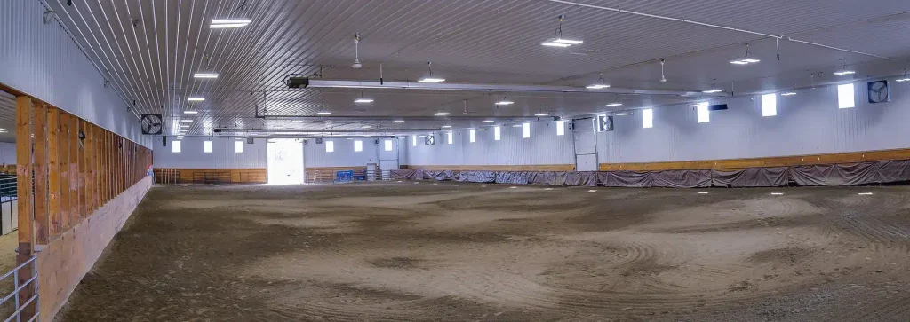 A buckskin post-frame riding arena with two overhead doors