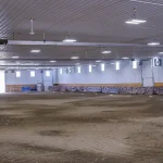 A buckskin post-frame riding arena with two overhead doors