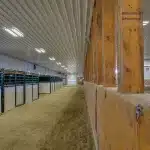 A buckskin post-frame riding arena with two overhead doors