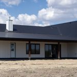 A white white post-frame Homestead with loft, with an overhead door, soffits, and timber accents