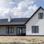 A white white post-frame Homestead with loft, with an overhead door, soffits, and timber accents
