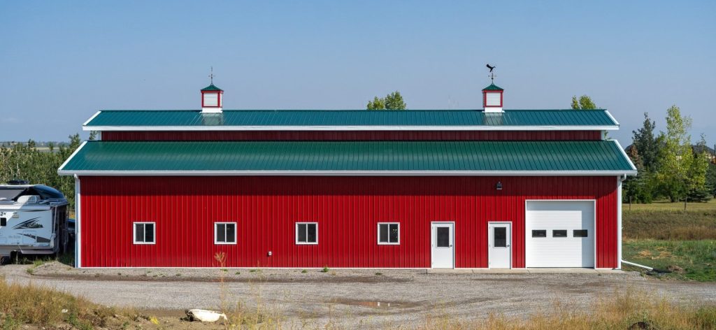 A dark red post-frame equestrian barn with a unique custom cupola