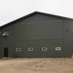 A Dark Sage post-frame agricultural shop with two overhead doors, a bi-fold door, an open and closed lean-to and soffits