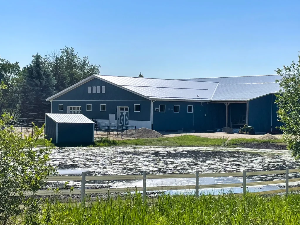 A slate blue post-frame equestrian riding arena