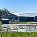 A slate blue post-frame equestrian riding arena