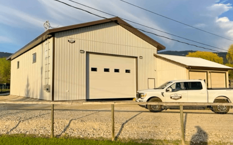 A white white post-frame lifestyle & hobby shop with a overhead door and open lean-to
