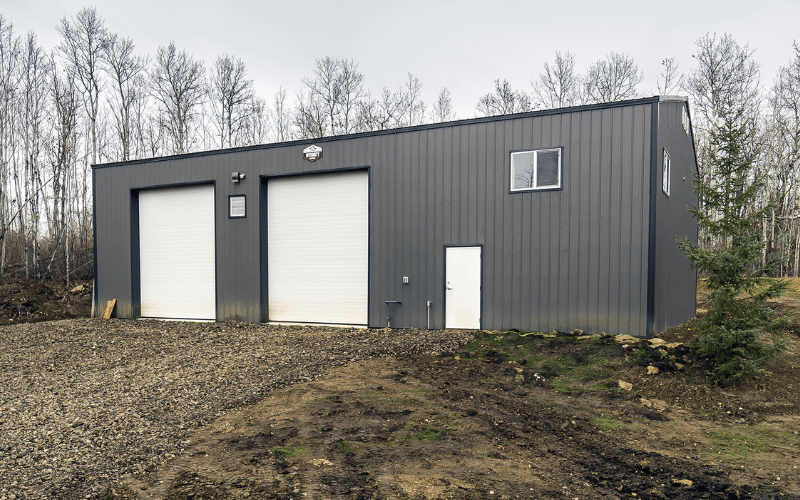 A charcoal post-frame agricultural shop with two overhead doors
