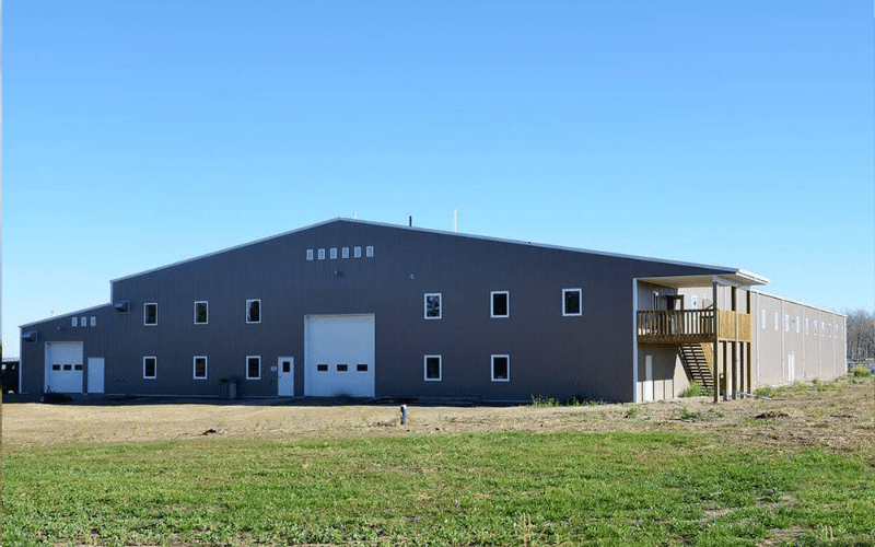 A buckskin post-frame riding arena with two overhead doors