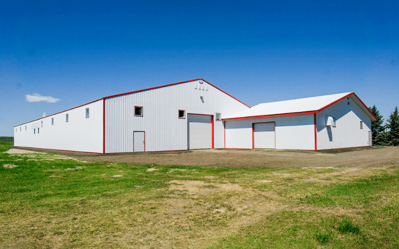 A bright white post-frame riding arena with two overhead doors