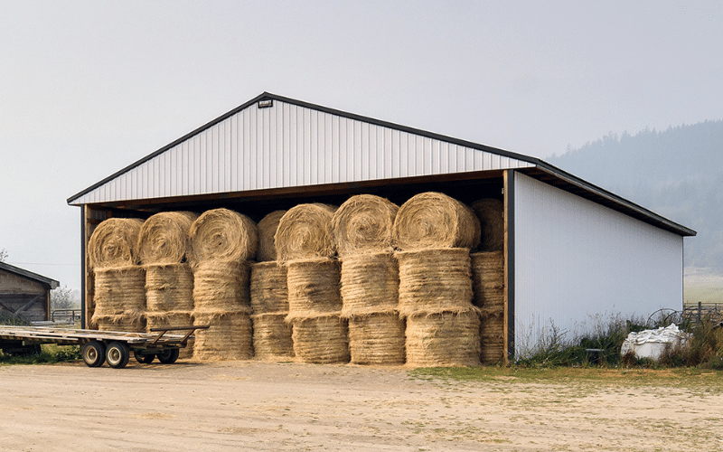A bright white partially open post-frame hay shed