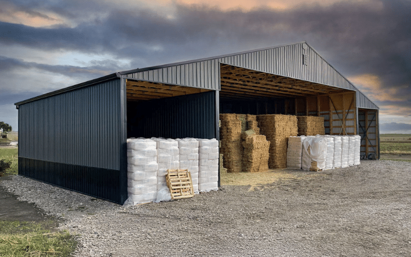 A gunmetal partially open post-frame hayshed