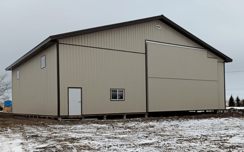 A wicker post-frame agricultural shop with two overhead doors, a bi-fold door, and soffits.