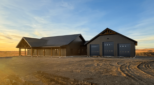 A coffee brown post-frame barndominium with three overhead doors, timber accents, soffits, and open and closed lean-tos