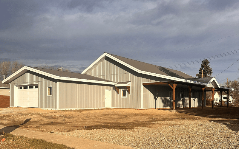 A bright white post-frame Ranch Hand with an attached garage, soffits, two open lean-tos and overhead door