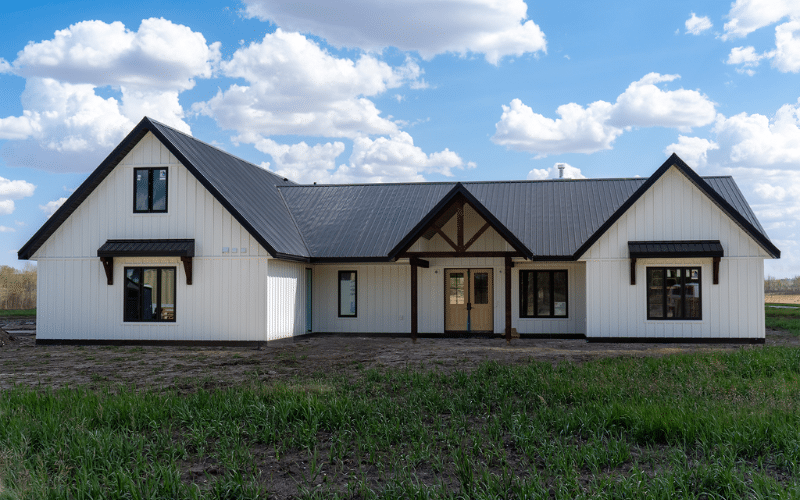 A white white post-frame Homestead with loft, with an overhead door, soffits, and timber accents