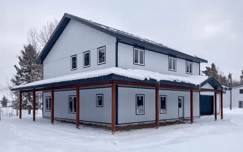 A white post-frame Farm House with open lean-tos, one overhead door, and soffits