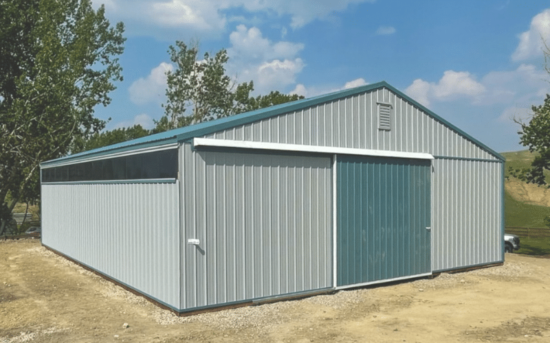 An ascot grey post-frame agricultural storage building with sliding doors and wall lights
