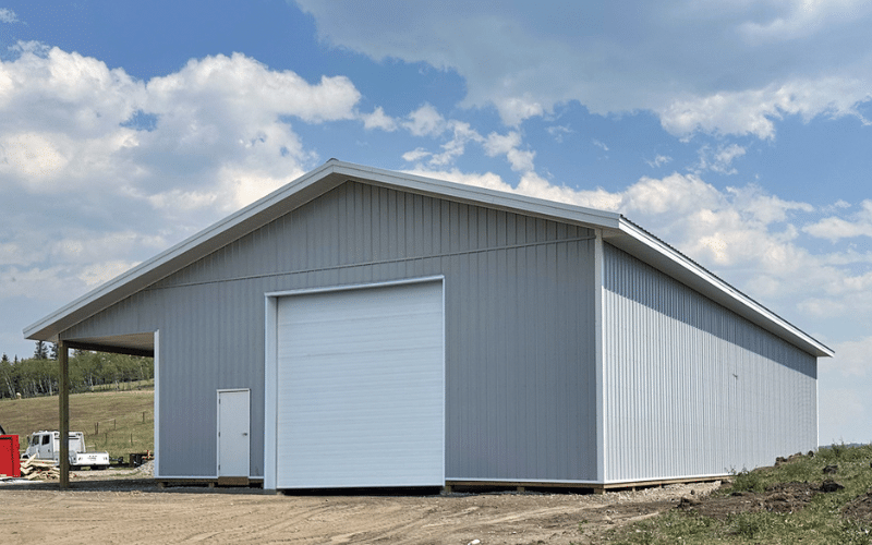 An ascot grey post-frame lifestyle & hobby storage building with overhead door, and an open lean-to