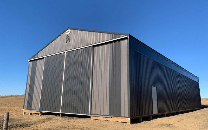 A charcoal post-frame agricultural shop with two sliding doors