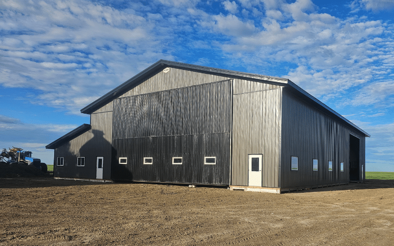 A charcoal post-frame agricultural shop with a closed lean-to, a bi-fold and overhead door
