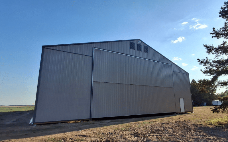 A sea wolf post-frame agricultural machine shed with a bi-fold and overhead door
