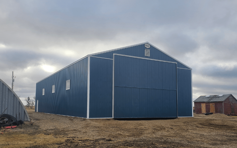 A heron blue post-frame agricultural storage building with two bi-fold doors