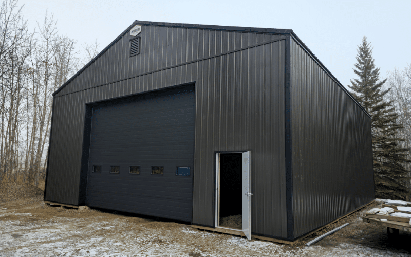 A dark brown post-frame agricultural shop with an overhead door