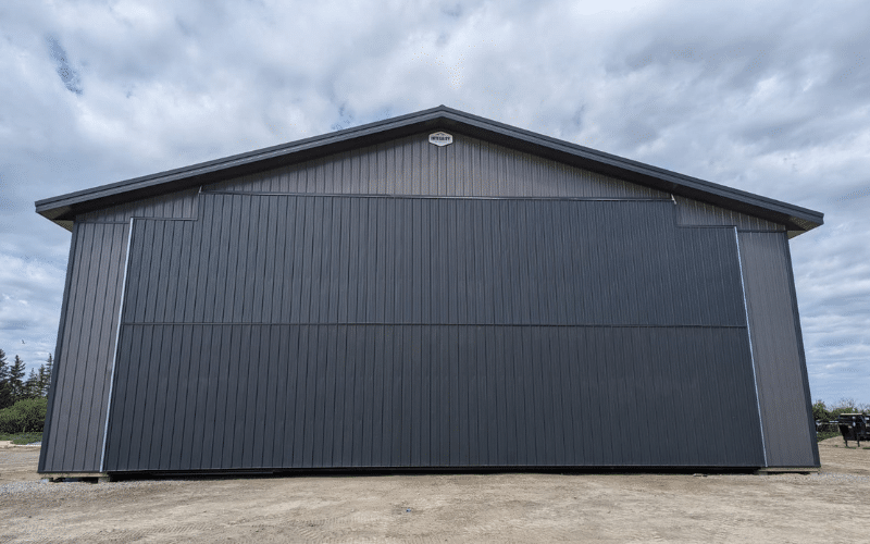 A charcoal post-frame agricultural shop with bi-fold and overhead doors