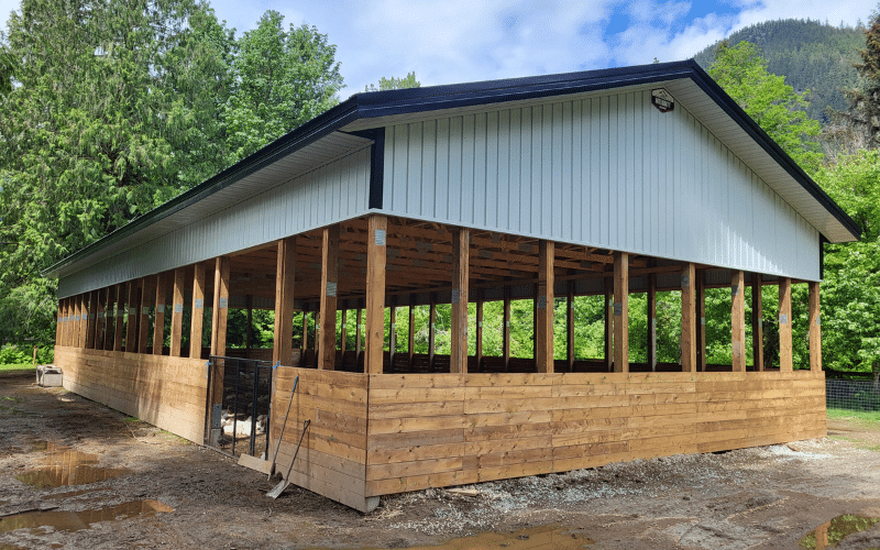 An open post-frame equestrian riding arena with kick wall and soffits
