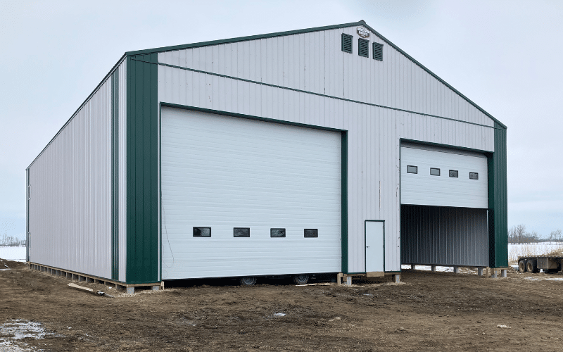 A white white post-frame agricultural shop with two overhead doors