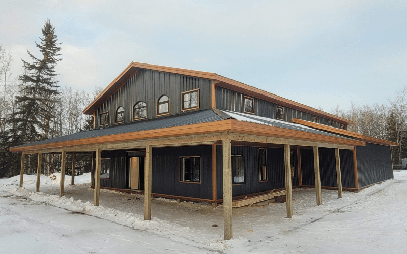 An iron ore post-frame commercial shop with a wrap around open lean-to and closed lean-to with soffits and an overhead door