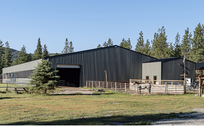 A dark sage post-frame equestrian Riding Arena with overhead doors and skylight