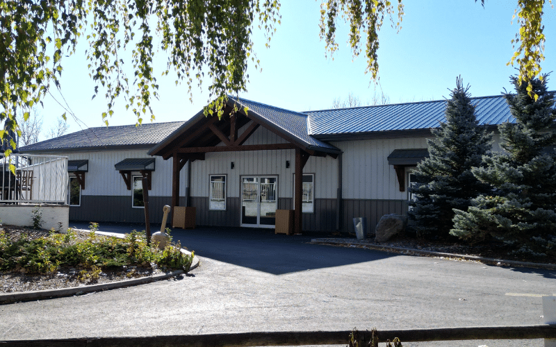 A white white post-frame commercial golf cart storage with open lean-tos, timber accents, cupolas, and soffits