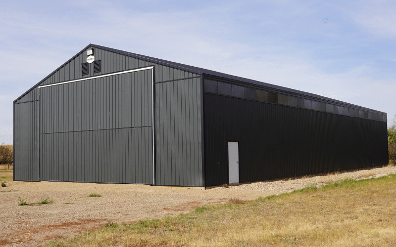 A Iron Ore post-frame agricultural storage building with a bi-fold door and wall lights