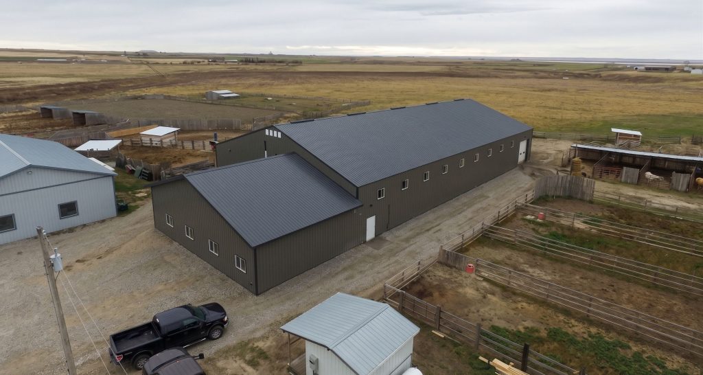 A sable post-frame riding arena with overhead doors, an open lean-to and kickwall