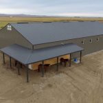 A sable post-frame riding arena with overhead doors, an open lean-to and kickwall