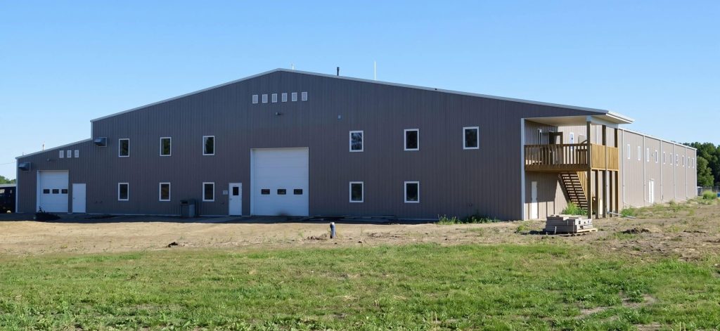 A buckskin post-frame riding arena with two overhead doors