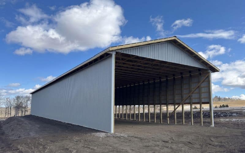 A post-frame equestrian hay shed with one side open