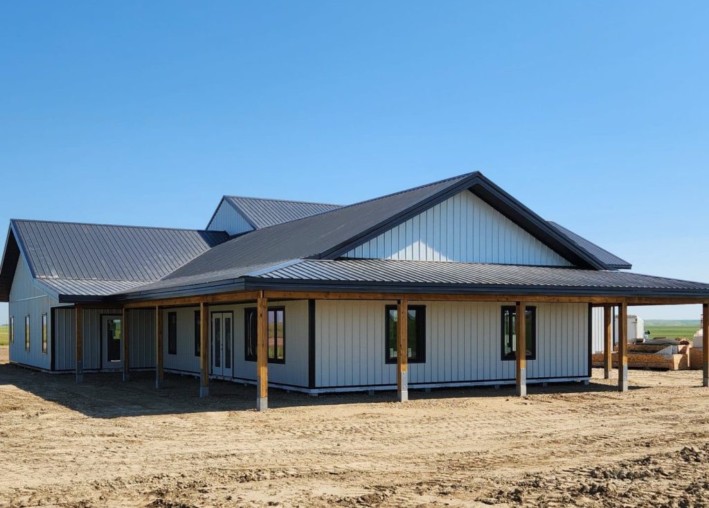 A white white post-frame custom residential build with soffits, open lean-to porch, and overhead doors