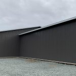 A charcoal post-frame equestrian riding arena