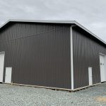 A charcoal post-frame equestrian riding arena